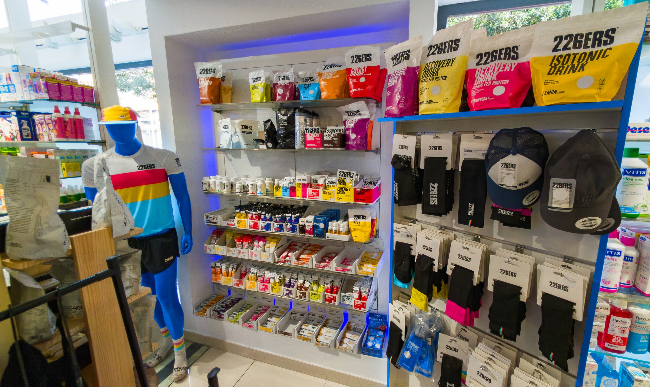 Se muestra una mujer con ropa deportiva con un batido saludable y un móvil en la otra mano